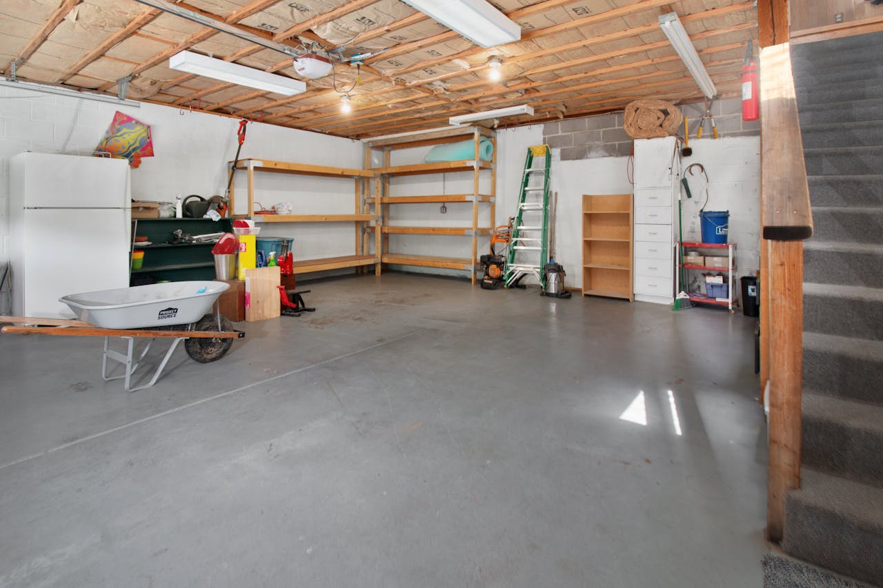 Spacious garage interior with storage shelves, tools, and a wheelbarrow, ideal for home organization.